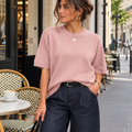 Pull femme manches courtes rose poudrée  porté avec jean large bleu foncé.