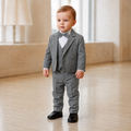 Bébé garçon portant un costume de cérémonie gris avec gilet, nœud papillon et chemise blanche plissée