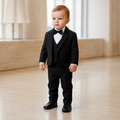 Bébé garçon portant un costume de cérémonie noir avec gilet, nœud papillon et chemise blanche plissée