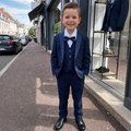 Garçon portant un costume de cérémonie bleu marine cinq pièces avec nœud papillon et chaussures noires